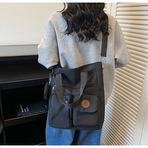 Vue détaillée du sac fourre-tout noir multi-poches montrant la texture en nylon et logo