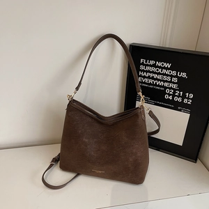 Détail de la texture en daim marron foncé et gravure dorée du logo de la marque