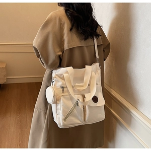 Détail d'un grand sac cabas beige multi-poches avec une petite pochette ronde suspendue