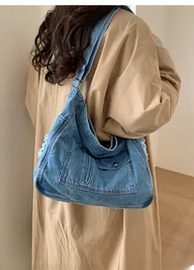 Detail of blue denim shoulder bag showing distressed fringe edges and jeans pocket design