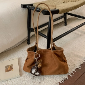 Detail of a brown suede tote bag featuring a leopard heart charm on a plush rug