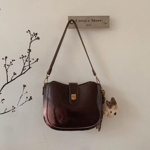 Detailed view of brown faux leather bucket bag with cute teddy bear charm on metal wall hook