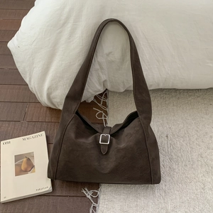 Detailed close-up of dark coffee suede shoulder bag with silver buckle and wide strap