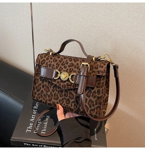 Dettaglio borsa leopardata con fibbia a cuore dorata e manico in pelle di classe