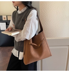 Close-up of a classic brown faux leather tote bag with elegant gold hardware details