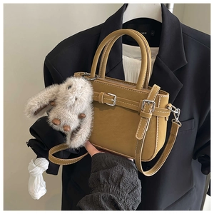 Detail of mustard yellow leather handbag with silver buckle and plush rabbit charm