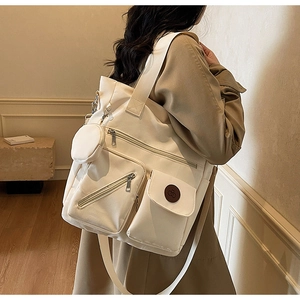 Détail du sac fourre-tout en toile crème avec design multi-poches et large bandoulière