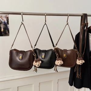 Close-up of three vintage saddle bags in coffee, black and brown with bear charms