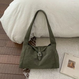 Detailed close-up of olive green suede tote bag with silver square buckle and wide strap