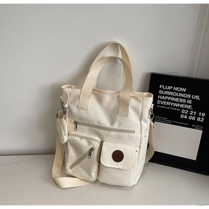 Gros plan d'un sac cabas blanc crème à poches multiples avec détails de porte-monnaie