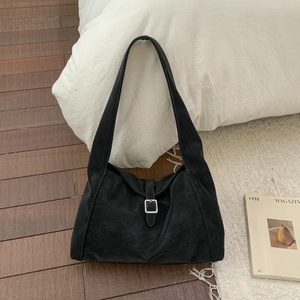 Detail of black suede shoulder bag featuring a square silver buckle and premium matte texture