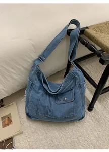 Detail of blue denim tote bag with metal buckles and distressed frayed edges on a rug