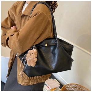 Detailed view of the black faux leather tote bag featuring a cute plush bear charm
