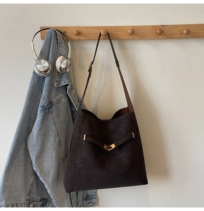 Detail of dark brown matte leather tote bag featuring gold matte metal buckle and strap