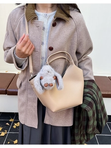 Détail du sac seau en cuir beige avec ouverture en V et breloque lapin mignonne