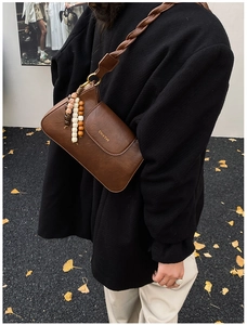 Close-up of brown faux leather crossbody bag featuring woven strap and beaded tassel detail