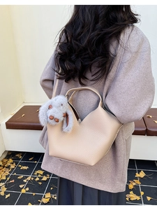 Détail du sac seau en cuir grainé beige avec un pendentif lapin en peluche doux