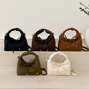 Detail showing five colors of suede handbags with knot handles and drawstring accents