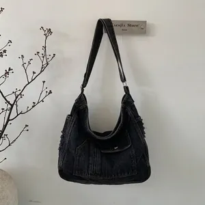 Detail of vintage black washed denim hobo bag featuring raw edges and external pocket