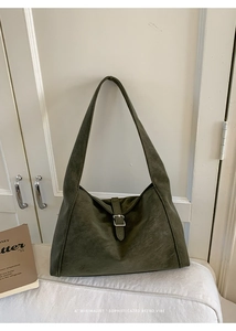 Close-up of dark green suede hobo bag featuring silver buckle and textured leather detail