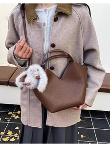 Détail d'un sac seau en cuir grainé marron foncé avec un charmant lapin en peluche