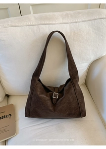 Detail of dark brown vintage faux leather handbag with silver buckle on a cozy sofa
