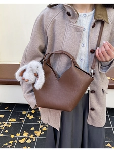 Détail du sac seau en cuir grainé marron foncé avec coupe en V et breloque lapin blanc