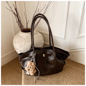 Macro detail of the dark brown textured leather tote with fine stitching and golden buckle
