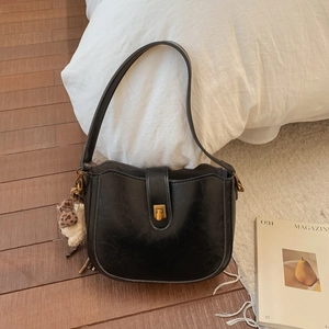 Close-up of black retro shoulder bag with golden clasp and leopard print bear charm