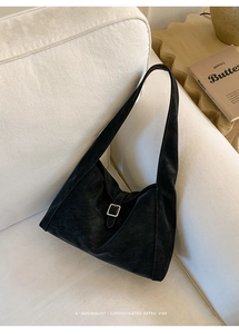 Detail shot of black suede shoulder bag with vintage silver buckle on a fabric sofa
