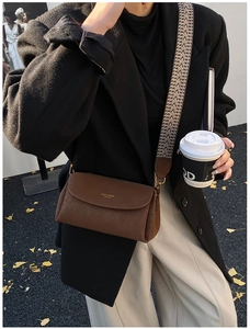 Détail de la sacoche en cuir marron avec bandoulière tissée géométrique et logo doré