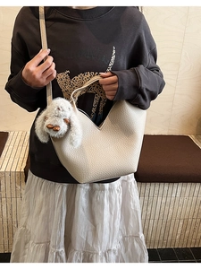 Détail d'un sac à main en cuir crème avec ouverture en V et breloque lapin en peluche doux