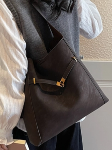 Minimalist dark brown suede bucket bag with gold buckle on a stylish model