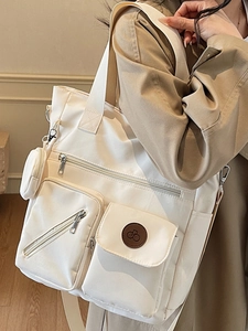 Grand sac cabas en nylon crème avec poches multiples porté par un mannequin pour le travail