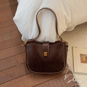 Detail of vintage brown shoulder bag showing antique gold square lock and cracked leather