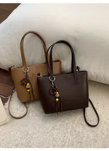 Detail of leather bucket bags with tassel and wood bead charms in cozy home setting