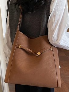 Brown suede tote bag with gold buckle shown on shoulder for a minimalist aesthetic