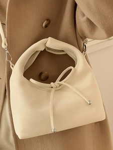 Elegant cream-colored lychee leather handbag with ring handle and delicate bow detail