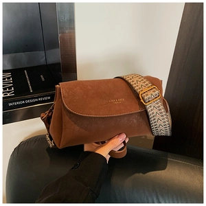 Gros plan d'un sac bandoulière vintage marron avec sangle jacquard et logo brodé