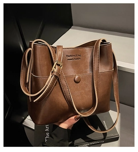 Détail d'un sac cabas rétro en cuir marron avec poche avant et logo doré élégant