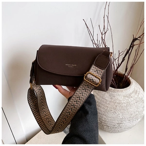 Détail du sac bandoulière en cuir marron foncé avec large bandoulière tissée à chevrons