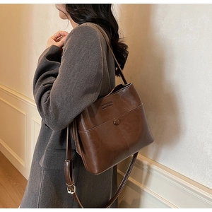 Détail du sac seau vintage en cuir marron avec poche à pression et bandoulière réglable