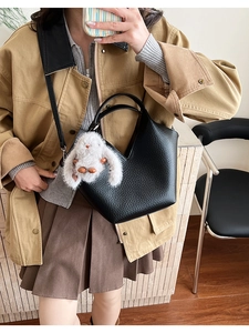 Détail d'un sac à main noir en cuir grainé avec un pendentif lapin en peluche mignon