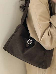 Brown matte suede tote bag with silver buckle worn by a model in a beige trench coat