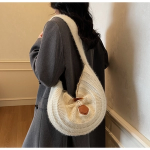 Detail view of cream knit shoulder bag with brown leather patch and horn buckle closure