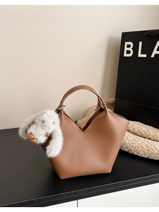 Détail de texture d'un sac en cuir grainé marron avec un joli pendentif de lapin blanc