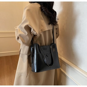 Détail du sac cabas en cuir noir brillant avec fermoir magnétique et texte logo mode