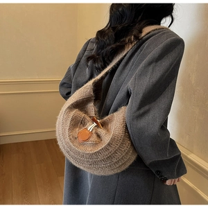 Detail of a brown knit crescent bag featuring a wooden horn button and leather patch