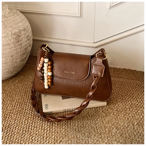 Detail of vintage brown PU leather handbag with braided strap and colorful bead tassel