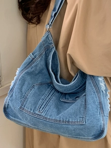 Blue denim tote bag with structured pockets and distressed fringe details for daily commuting